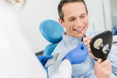 Smiling patient comparing tooth shades with dentist